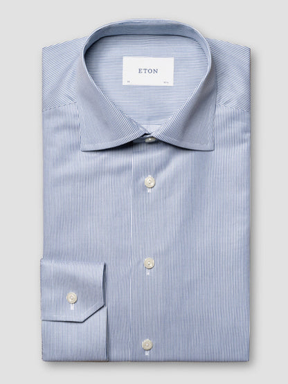 The Eton Contemporary Fit Fine Striped Signature Twill Dress Shirt in Mid Blue features white pinstripes, a spread collar, and white buttons. The "ETON" label inside the collar completes this business classic.