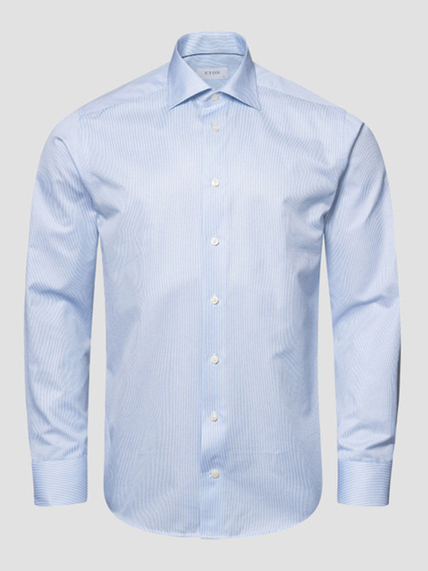 The Eton Contemporary Fit Fine Striped Signature Twill Dress Shirt in light blue, featuring long sleeves and a subtle striped pattern, is shown against a plain gray background.