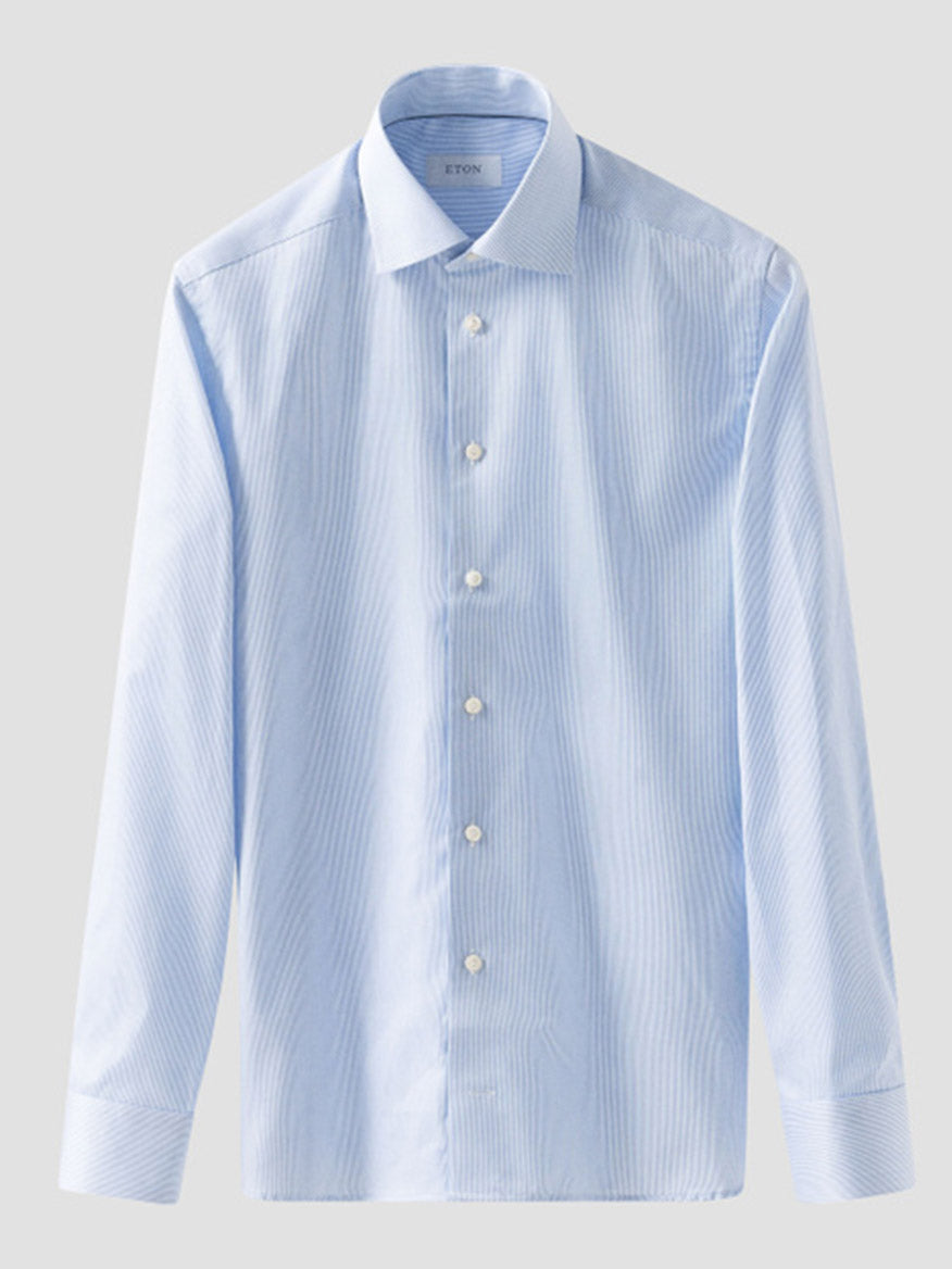 The Eton Contemporary Fit Fine Striped Signature Twill Dress Shirt in light blue features long sleeves, a spread collar, white buttons, and a subtle stripe pattern—perfect for business style. Shown on a plain gray background.