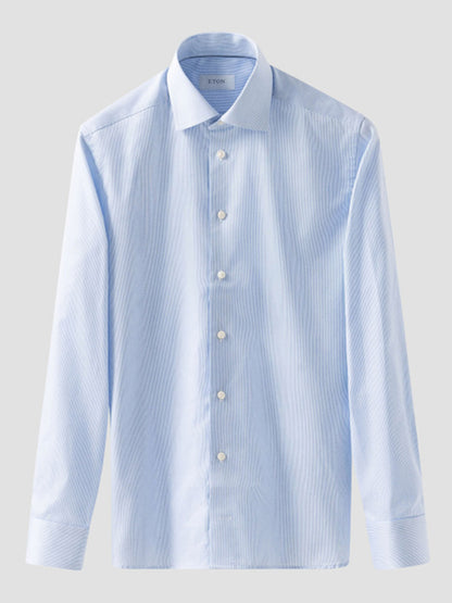 The Eton Slim Fit Fine Striped Signature Twill Dress Shirt in Light Blue features a cut away collar and subtle vertical stripes, shown on a plain background.