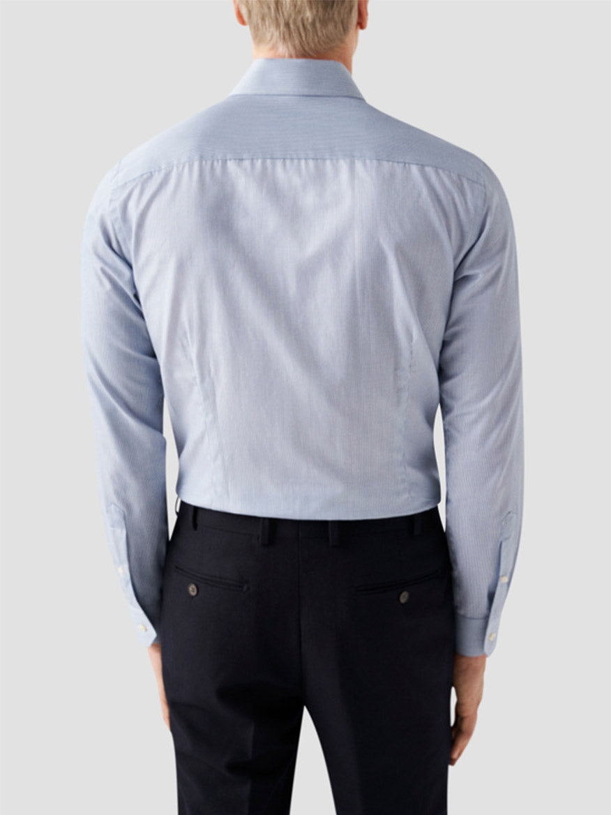A man is shown from the back wearing an Eton Slim Fit Fine Striped Signature Twill Dress Shirt in Mid Blue and black dress pants against a plain light gray background, highlighting a timeless business classic style.
