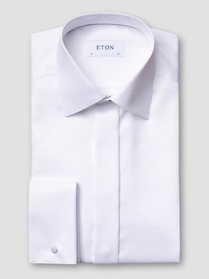 The Eton Slim Fit Fly Front Evening Dobby Shirt in White, featuring a pointed collar and French cuffs, is neatly folded with the “Eton” label visible inside the collar against a plain light gray background.