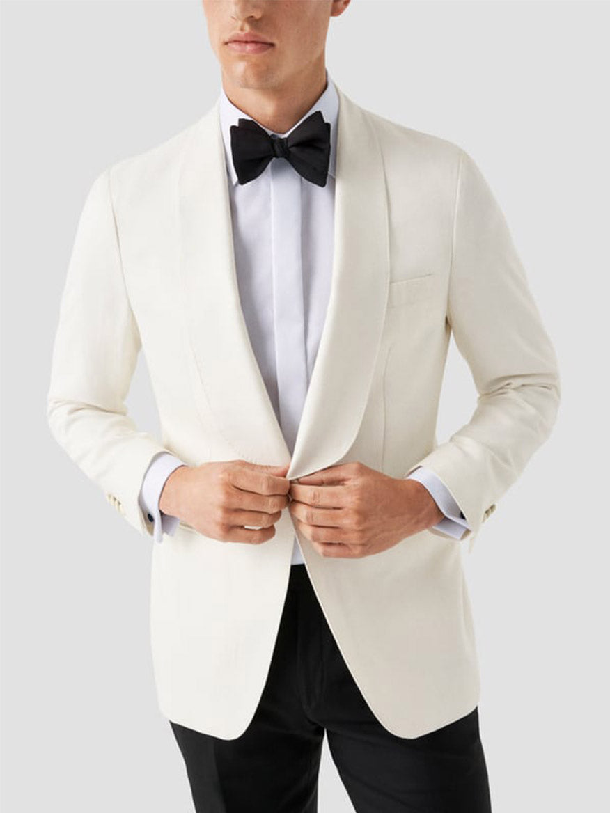 A man in a white tuxedo jacket, black bow tie, black pants, and the Eton Contemporary Fit Fly Front Signature Twill Evening Shirt in White, buttoning his jacket against a plain light background.