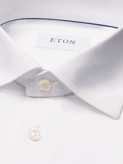 Close-up of the Eton Slim Fit White Four-Way Stretch Shirt, featuring a pointed collar, white buttons, and a visible Eton label inside the collar—a crisp shirt designed for modern elegance.