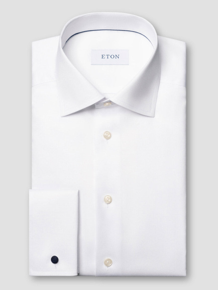 A neatly folded Eton Contemporary Fit Solid Signature Twill Dress Shirt in White with French cuffs is displayed against a light gray background.