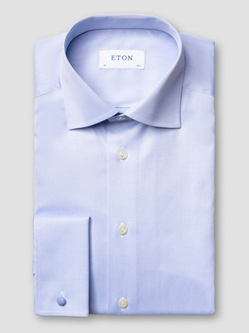 The Eton Contemporary Fit Solid Signature Twill Dress Shirt in Light Blue features a spread collar, French cuffs, white buttons, and is crafted from organic cotton twill—neatly folded and displayed on a plain background.