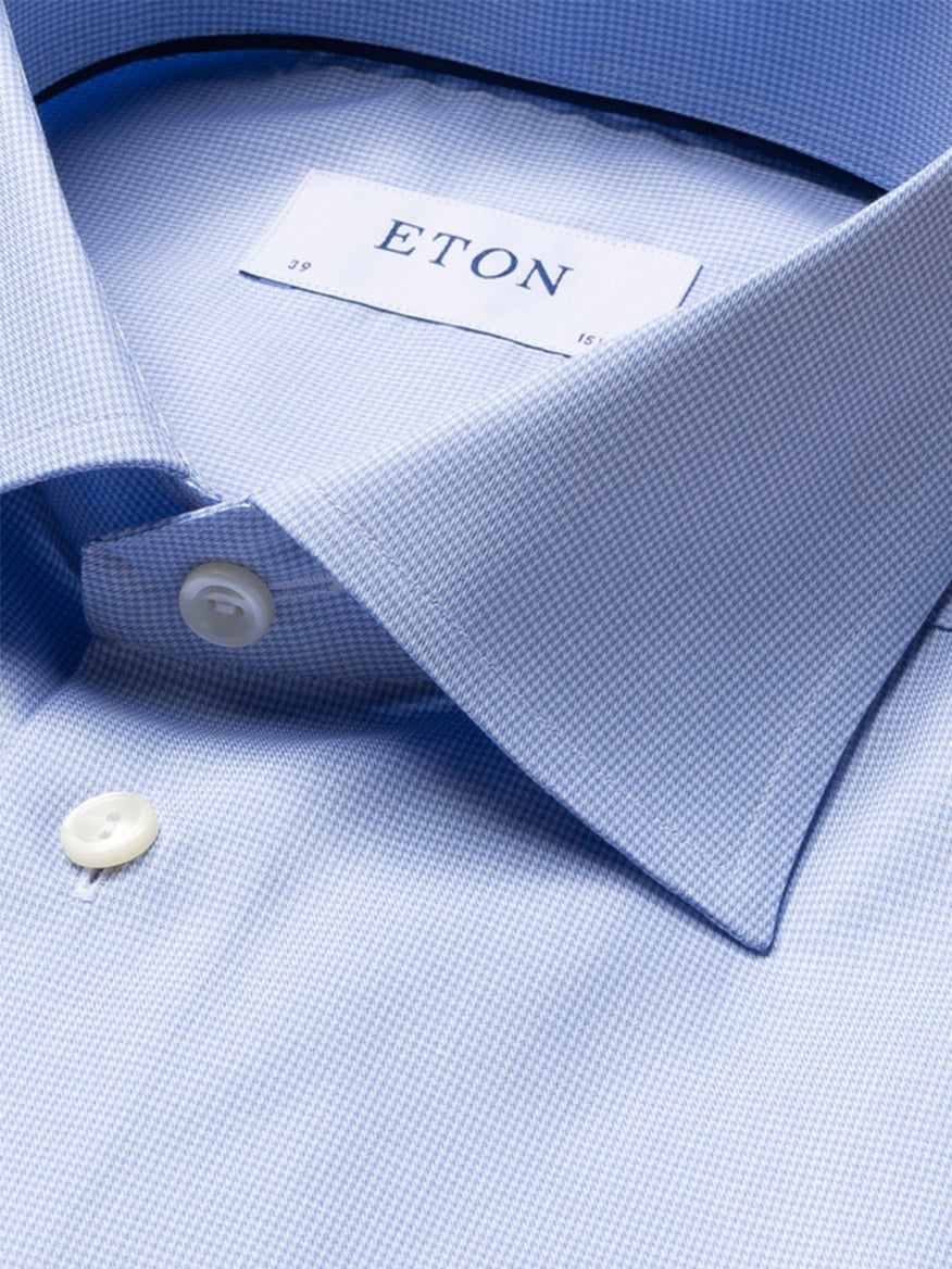 Close-up of a neatly folded Eton Contemporary Fit Light Blue Houndstooth Dress Shirt, featuring white buttons and the visible brand label.