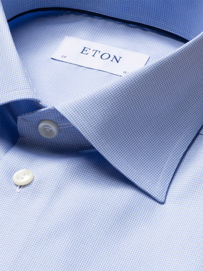 Close-up of a neatly folded Eton Contemporary Fit Light Blue Houndstooth Dress Shirt, featuring white buttons and the visible brand label.