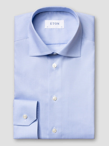A neatly folded Eton Slim Fit Houndstooth Fine Twill Dress Shirt in light blue, featuring white buttons, a single cuff, and an "ETON" label inside the collar.