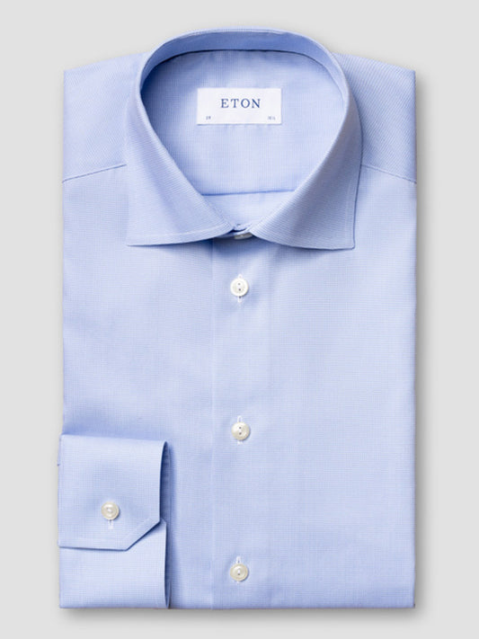 A neatly folded Eton Slim Fit Houndstooth Fine Twill Dress Shirt in light blue, featuring white buttons, a single cuff, and an "ETON" label inside the collar.