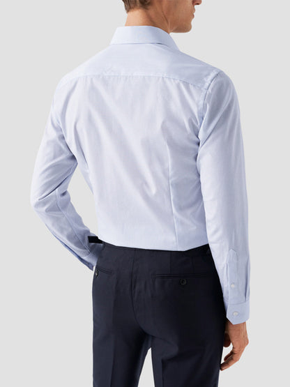 A man is shown from the back, hands on hips, wearing an Eton Contemporary Fit Sky Blue Micro Print Dress Shirt and dark trousers.