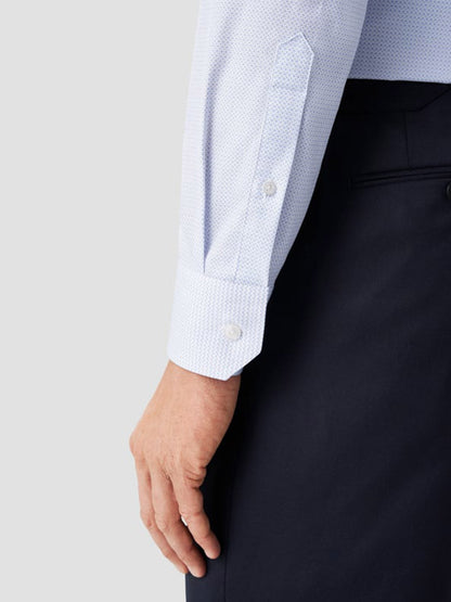 A person wears the Eton Contemporary Fit Sky Blue Micro Print Dress Shirt with a cut away collar and dark trousers, their left arm relaxed at their side, displaying the shirt cuff and buttons.