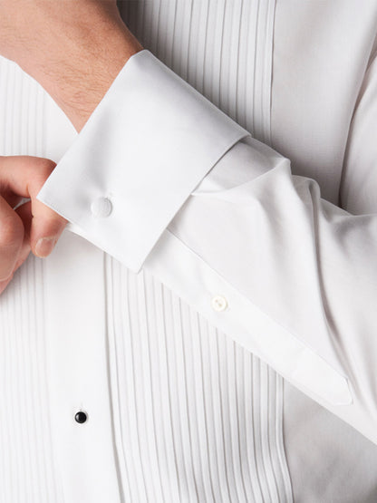 A person adjusts the cuff of an Eton Contemporary Fit Plissé Black Tie Dress Shirt, which features a pleated front and covered buttons.