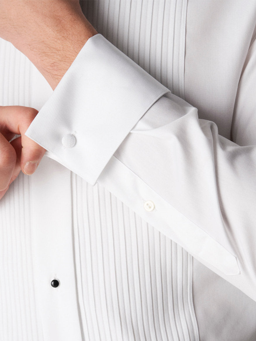 Someone adjusts the cuff of the Eton Slim Fit Plissé Bib-Front Tuxedo Shirt in White, a classic black-tie shirt featuring a fabric-covered button on the cuff.