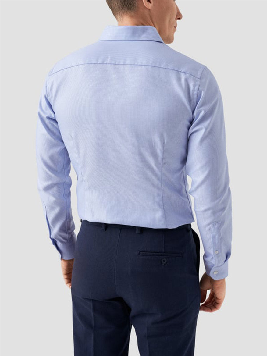 A man wearing the Eton Contemporary Fit Semi Solid Dobby Dress Shirt in Light Blue and dark navy trousers, viewed from the back against a plain light gray background.