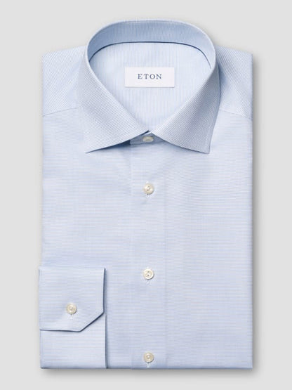 The Eton Contemporary Fit Semi Solid Dress Shirt in Light Blue features a pointed collar, white buttons, and a neatly folded design with the "ETON" label inside the collar.