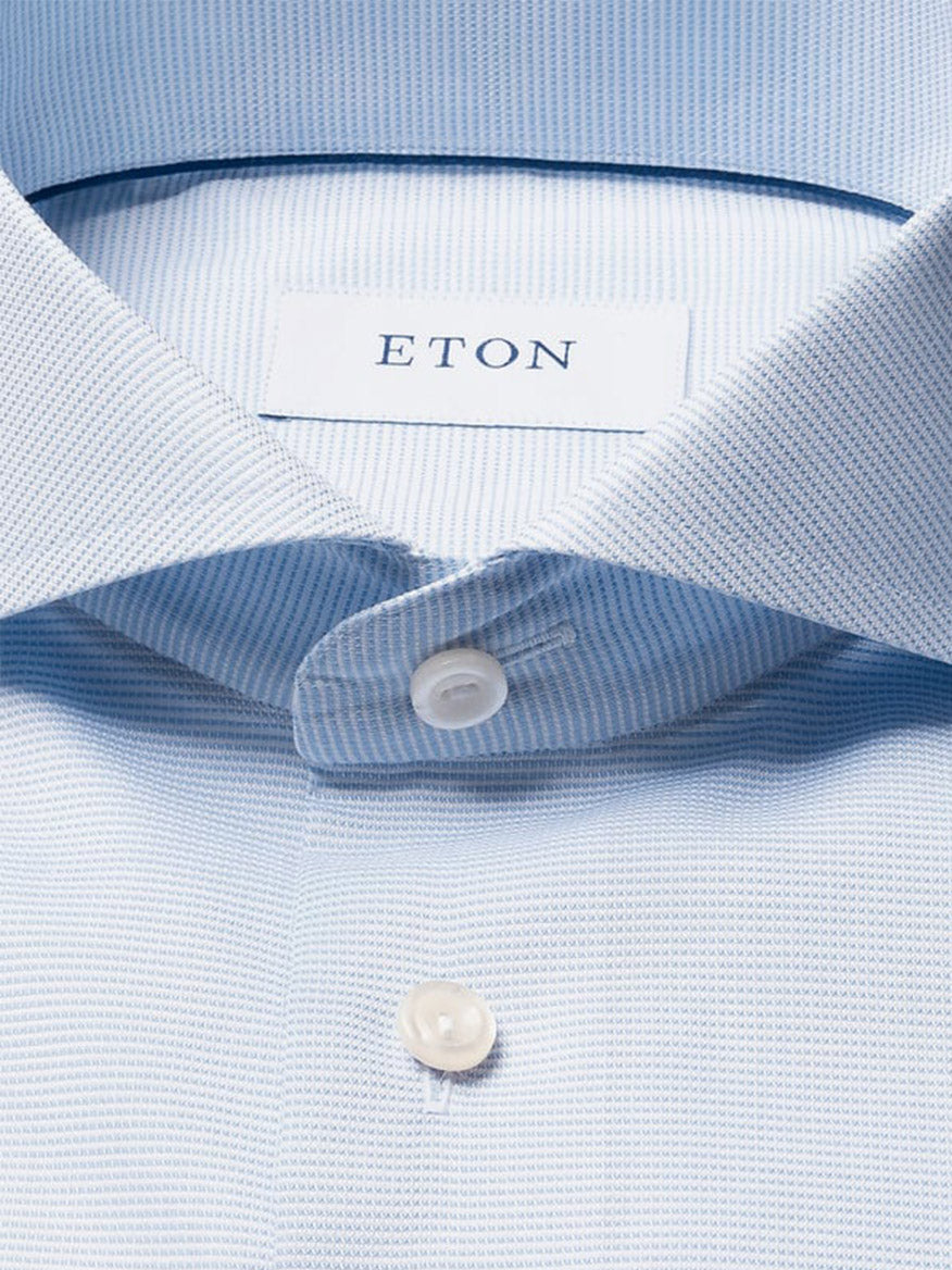 Close-up of an Eton Slim Fit Semi Solid Dress Shirt in light blue, featuring white buttons and an extreme cut away collar, with the "ETON" brand label inside the collar.