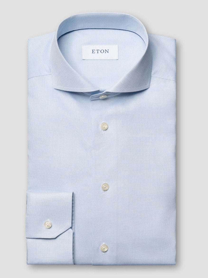 The Eton Slim Fit Semi Solid Dress Shirt in Light Blue, with an extreme cut away collar, is neatly folded and displayed on a plain grey background.