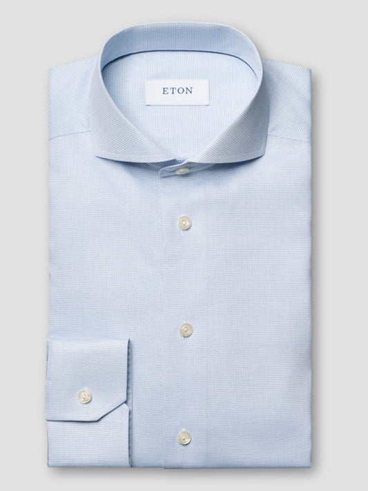 The Eton Slim Fit Semi Solid Dress Shirt in Light Blue, with an extreme cut away collar, is neatly folded and displayed on a plain grey background.
