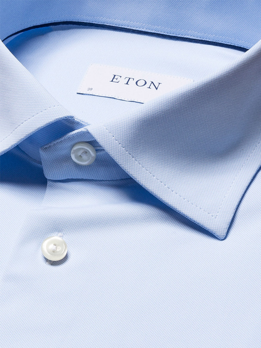 Close-up of a neatly folded Eton Slim Fit Semi Solid Four-Way Stretch Shirt in Light Blue, featuring a spread collar and white buttons with the Eton brand label on the inside collar.