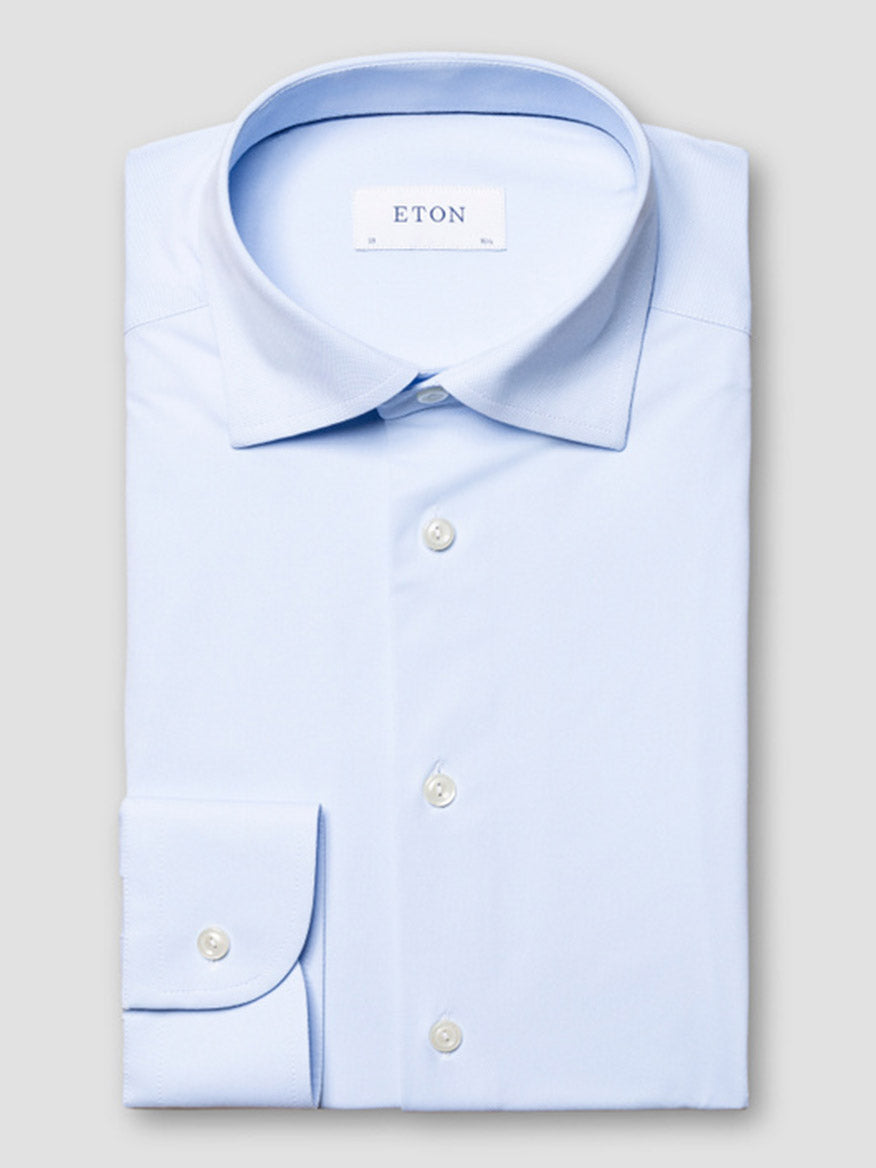 A neatly folded Eton Slim Fit Semi Solid Four-Way Stretch Shirt in light blue with white buttons and a visible "ETON" label inside the collar, displayed on a plain background.