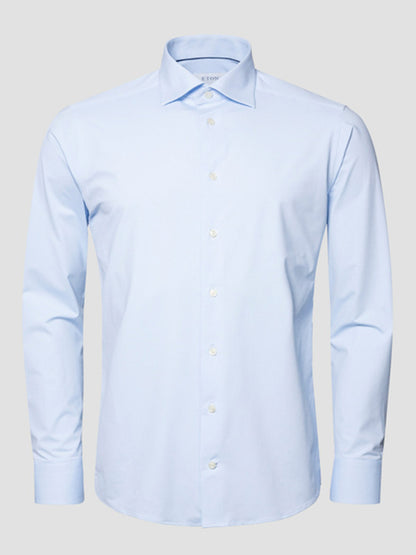 The Eton Slim Fit Semi Solid Four-Way Stretch Shirt in Light Blue, featuring long sleeves and a button-up design, is shown against a plain gray background.