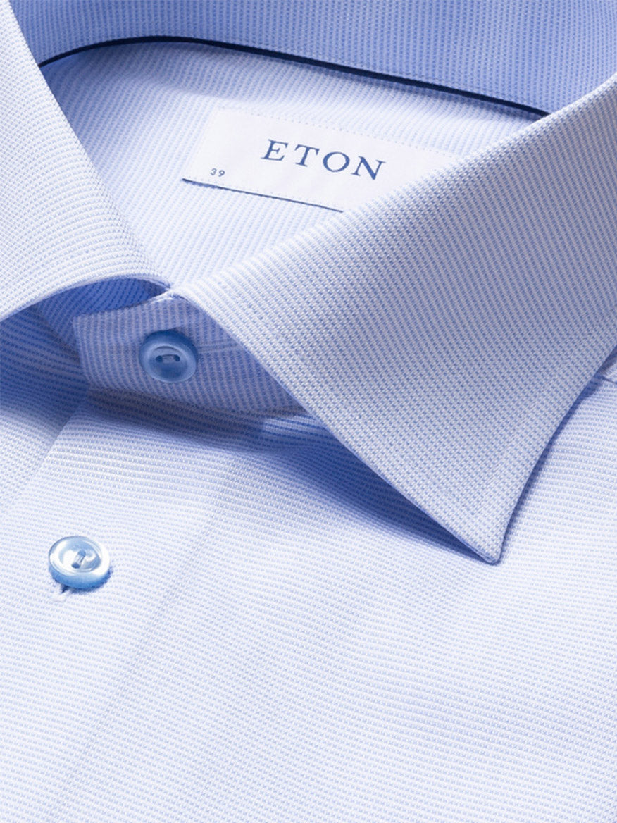 Close-up of the Eton Slim Fit Semi Solid Piping Details Shirt in light blue, featuring a subtle pattern, cutaway collar, button closure, and “ETON” label on the inside collar.