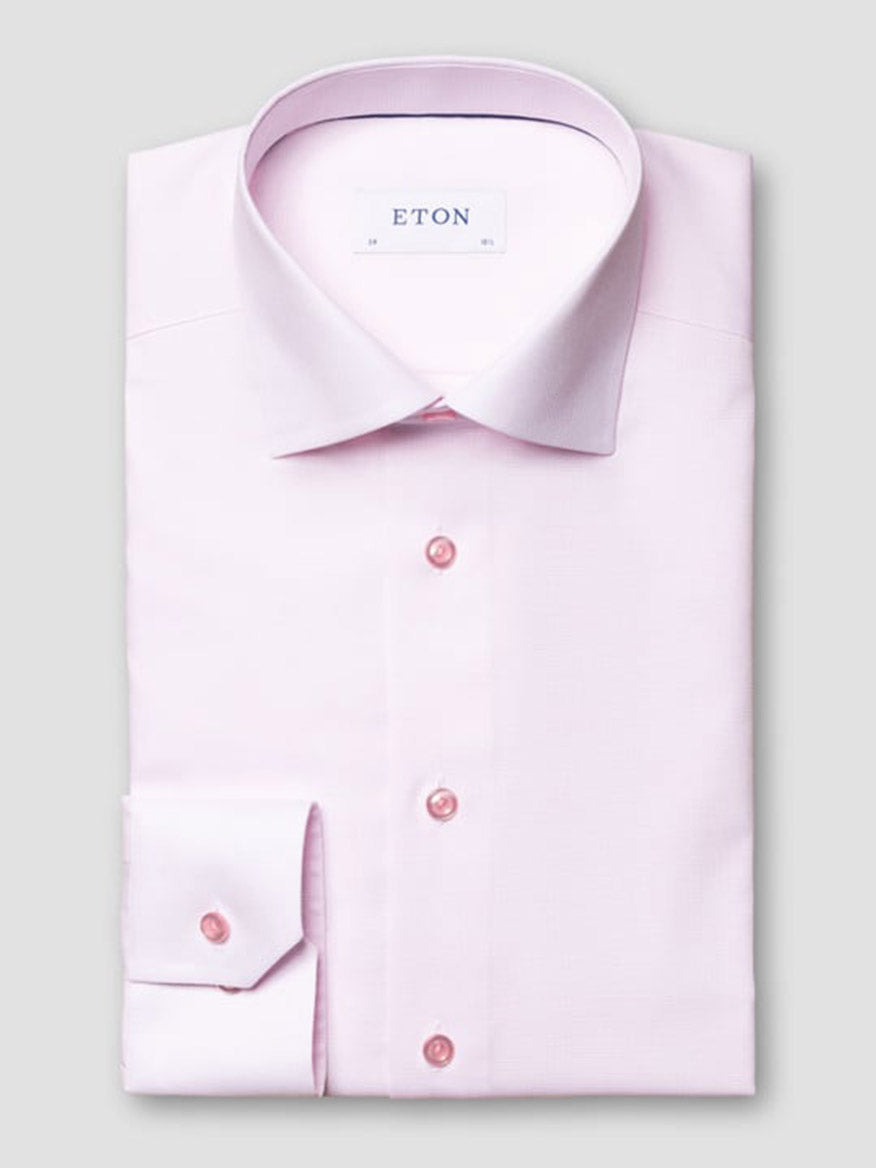 The Eton Slim Fit Semi Solid Piping Details Shirt in Pink features a spread collar and buttoned cuffs, neatly folded and displayed against a plain grey background.