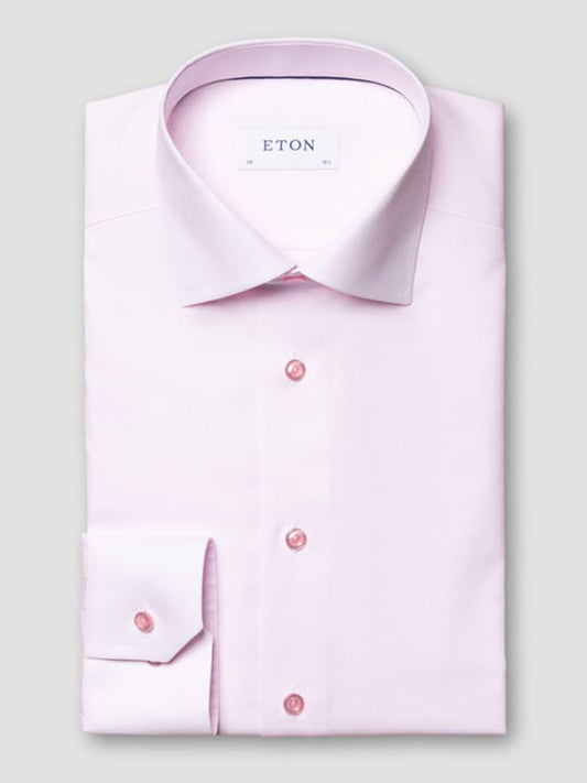 The Eton Slim Fit Semi Solid Piping Details Shirt in Pink features a spread collar and buttoned cuffs, neatly folded and displayed against a plain grey background.