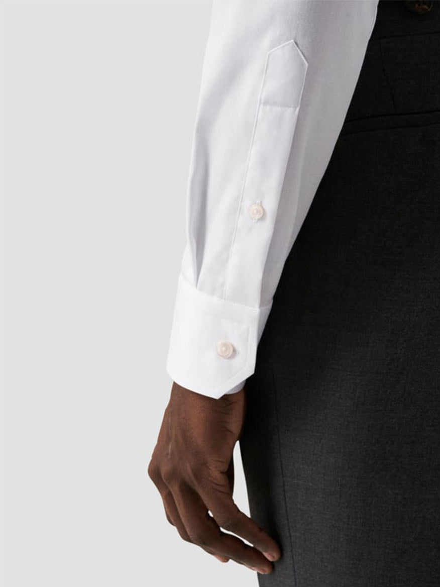 Close-up of a person wearing the Eton Contemporary Fit White Signature Twill Dress Shirt with buttoned cuffs and dark trousers, shown from the side against a plain background.