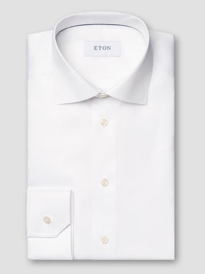 The Eton Contemporary Fit White Signature Twill Dress Shirt, featuring a pointed collar and buttoned cuffs, is neatly folded and displayed on a light gray background.