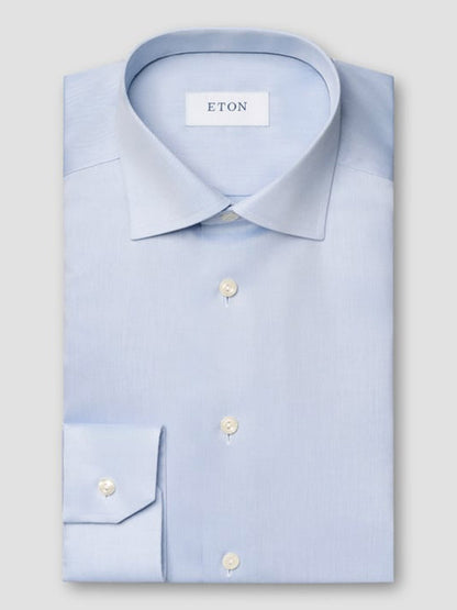 The Eton Contemporary Fit Light Blue Signature Twill Dress Shirt features a pointed collar, white buttons, and an Eton brand label inside the collar. Its wrinkle-free design ensures effortless style throughout the day.