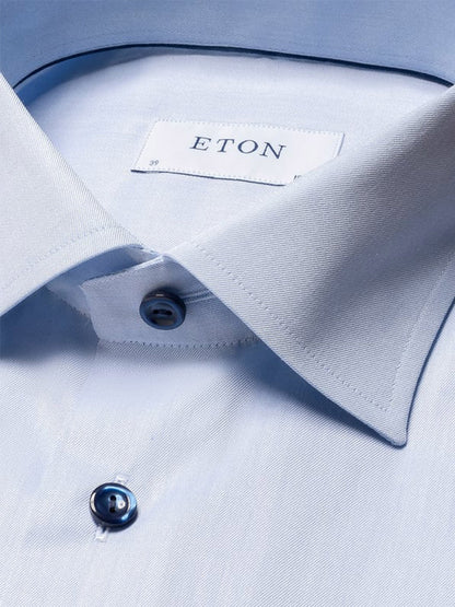 Close-up of the Eton Contemporary Fit Signature Twill Dress Shirt in light blue with navy details, featuring a pointed collar, fastened top button, and a visible Eton label inside the collar.