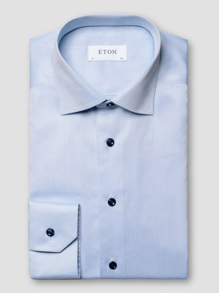 The Eton Contemporary Fit Signature Twill Dress Shirt in light blue features navy details, a pointed collar, long sleeves, dark buttons, and the "ETON" label inside the collar.