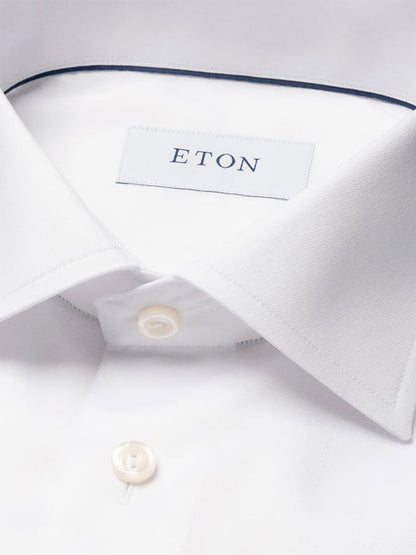 Close-up of the Eton Slim Fit Solid Signature Twill Dress Shirt in White, featuring a pointed collar, single cuff, white buttons, and an Eton brand label inside the neck.