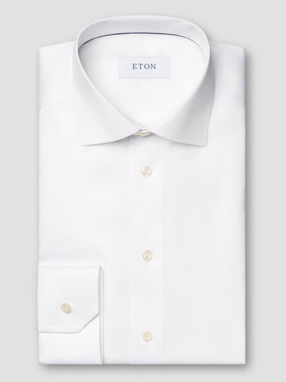 The Eton Slim Fit Solid Signature Twill Dress Shirt in White features a classic collar, single cuff, pearl buttons, and the Eton label inside the collar. Crafted from premium Signature Twill organic cotton.