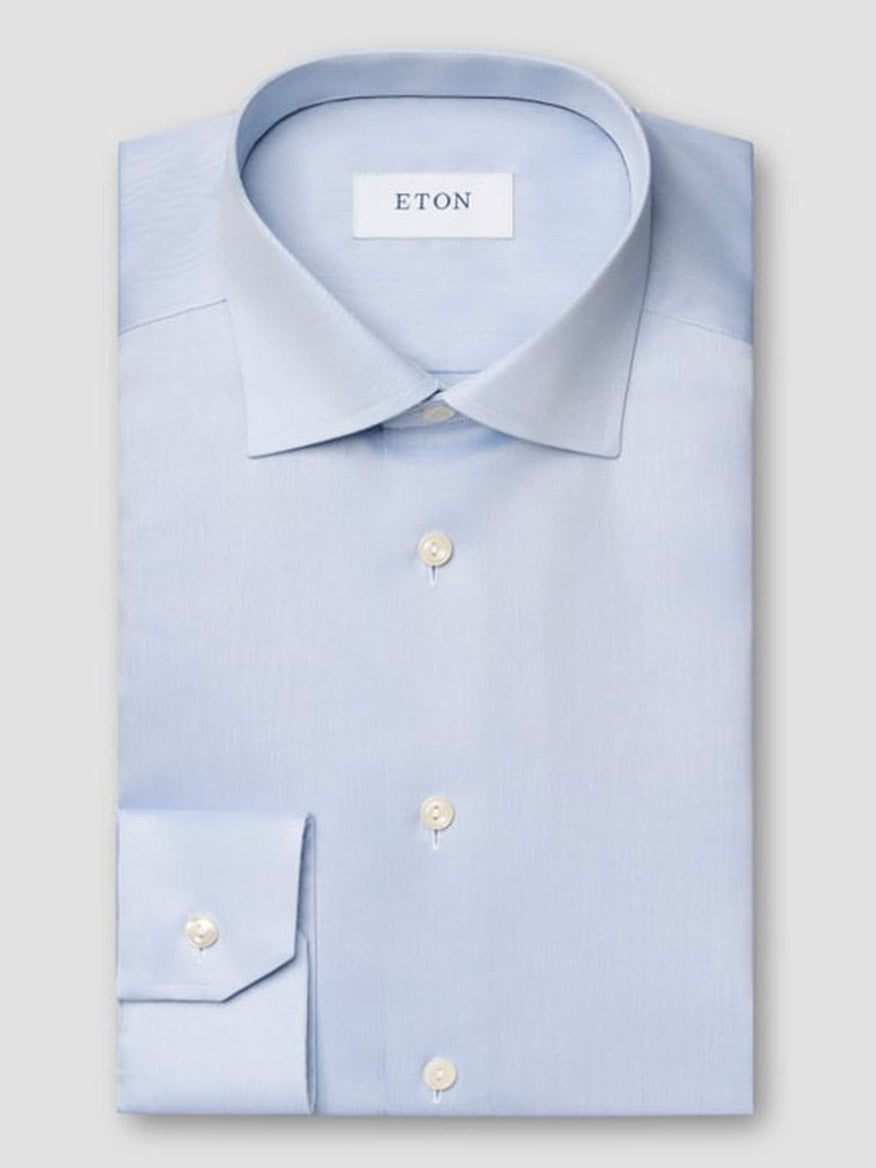 The Eton Slim Fit Solid Signature Twill Dress Shirt in Light Blue features a spread collar, single cuffs, and white buttons. This wrinkle-free shirt combines style and convenience, ideal for busy professionals.
