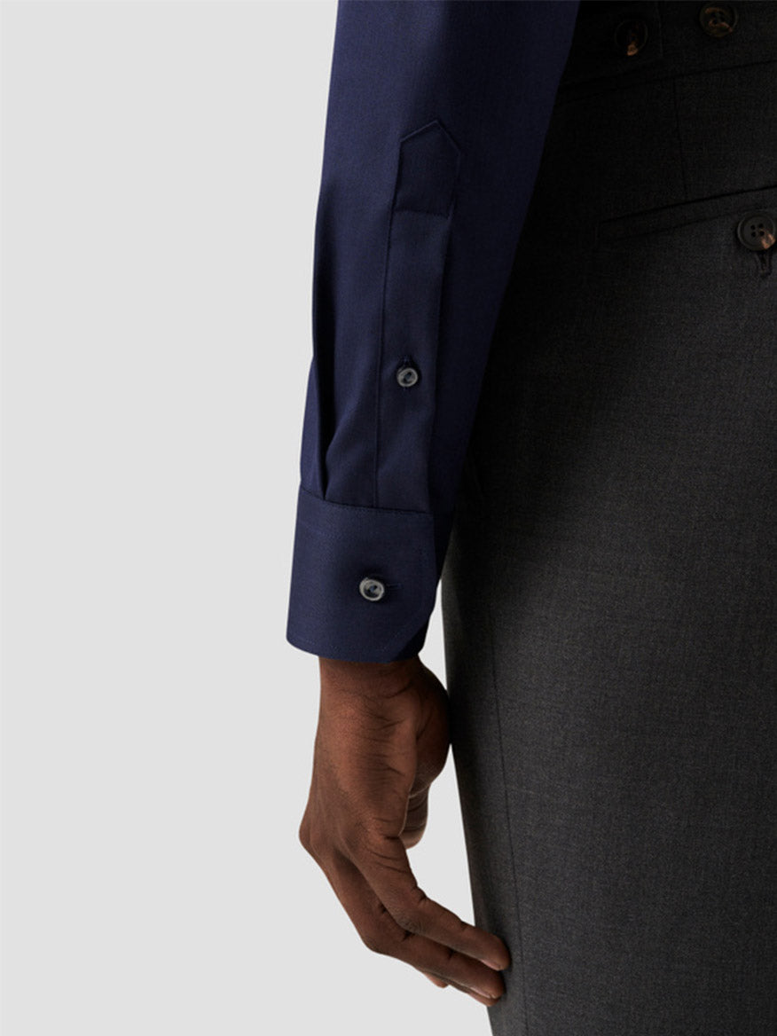 A person wears an Eton Slim Fit Solid Signature Twill Dress Shirt in Navy Blue with buttoned cuffs and dark gray trousers, shown from the waist down with their arm at their side.