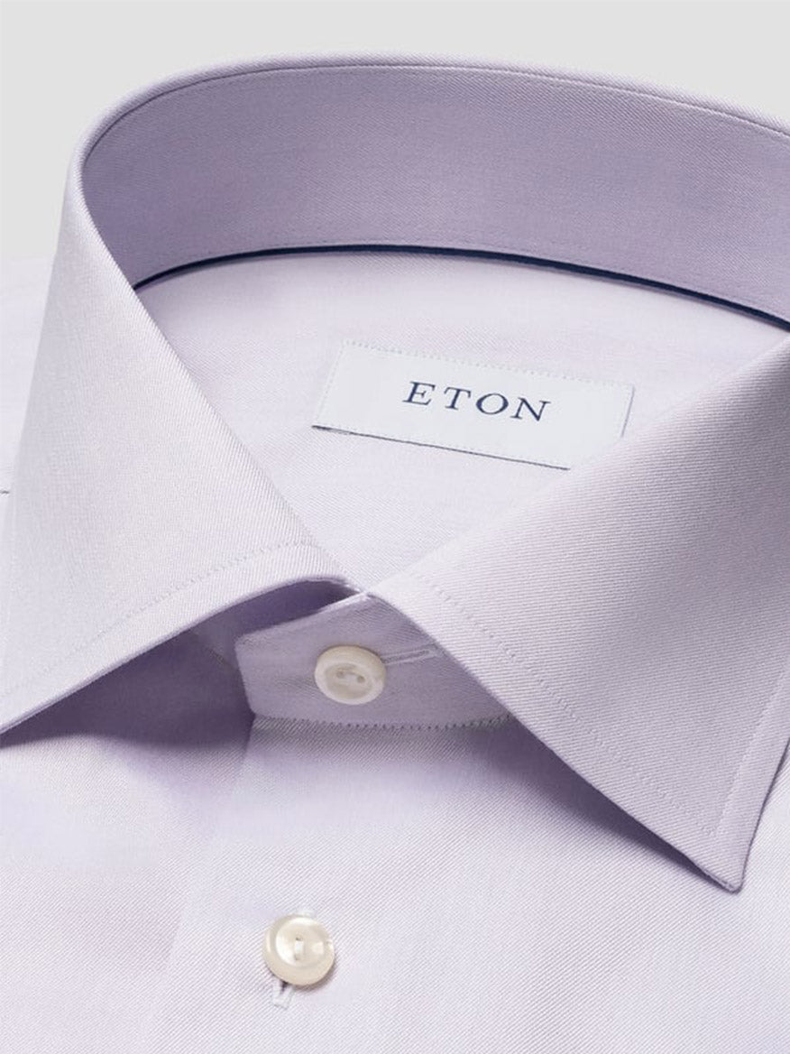 Close-up of a neatly folded Eton Slim Fit Solid Signature Twill Dress Shirt in Mid Purple with white buttons and an "ETON" label on the inside collar.