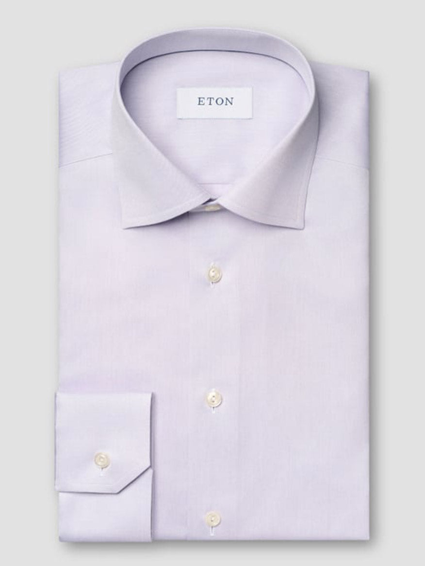 The Eton Slim Fit Solid Signature Twill Dress Shirt in Mid Purple features a pointed collar, buttoned cuffs, and the "ETON" label inside the collar. This neatly folded shirt offers a refined look for any professional setting.