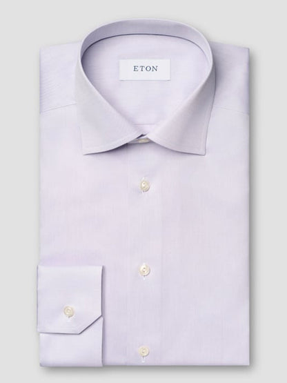 The Eton Slim Fit Solid Signature Twill Dress Shirt in Mid Purple features a pointed collar, buttoned cuffs, and the "ETON" label inside the collar. This neatly folded shirt offers a refined look for any professional setting.