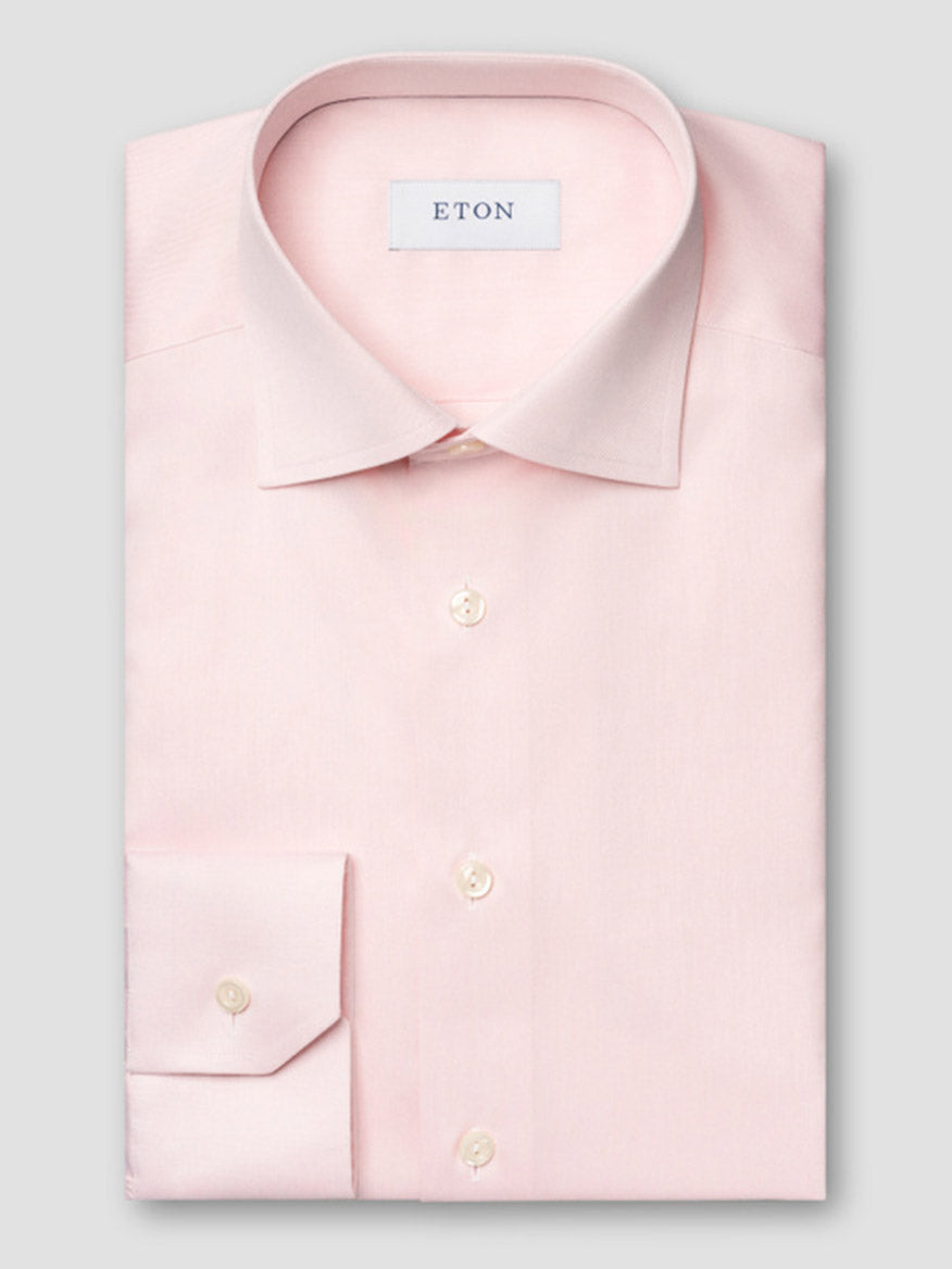 A neatly folded Eton Slim Fit Solid Signature Twill Dress Shirt in pink, featuring a classic collar, white buttons, and the Eton label inside the collar.