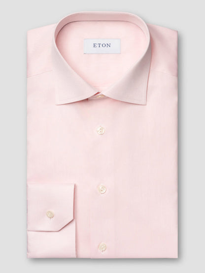 A neatly folded Eton Slim Fit Solid Signature Twill Dress Shirt in pink, featuring a classic collar, white buttons, and the Eton label inside the collar.
