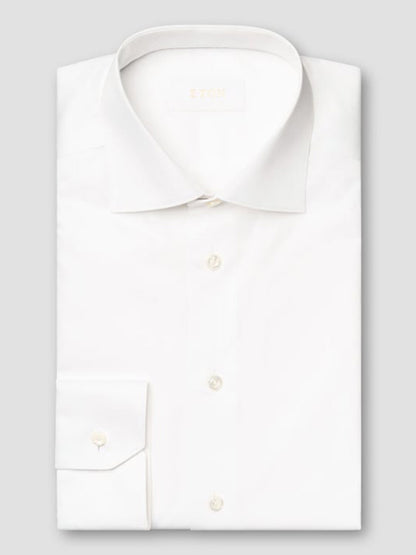 The Eton Contemporary Fit Solid Elevated Twill Dress Shirt in White features a classic collar and buttoned cuffs, neatly folded and displayed on a plain light gray background.