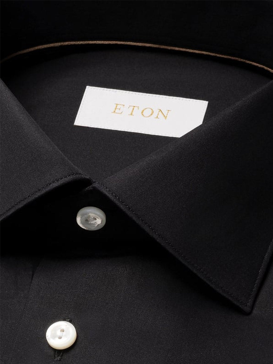 Close-up of the Eton Contemporary Fit Solid Elevated Twill Dress Shirt in Black, featuring white buttons, a visible "ETON" gold label inside the collar, and crafted from premium organic Supima cotton that's crease-resistant.