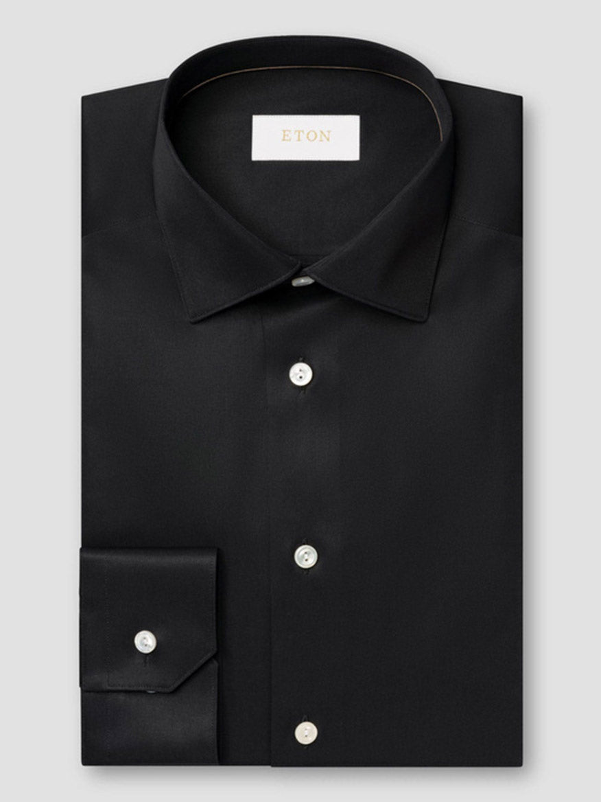 The Eton Contemporary Fit Solid Elevated Twill Dress Shirt in Black features white buttons and an "ETON" label inside the collar, neatly folded and displayed on a light gray background.
