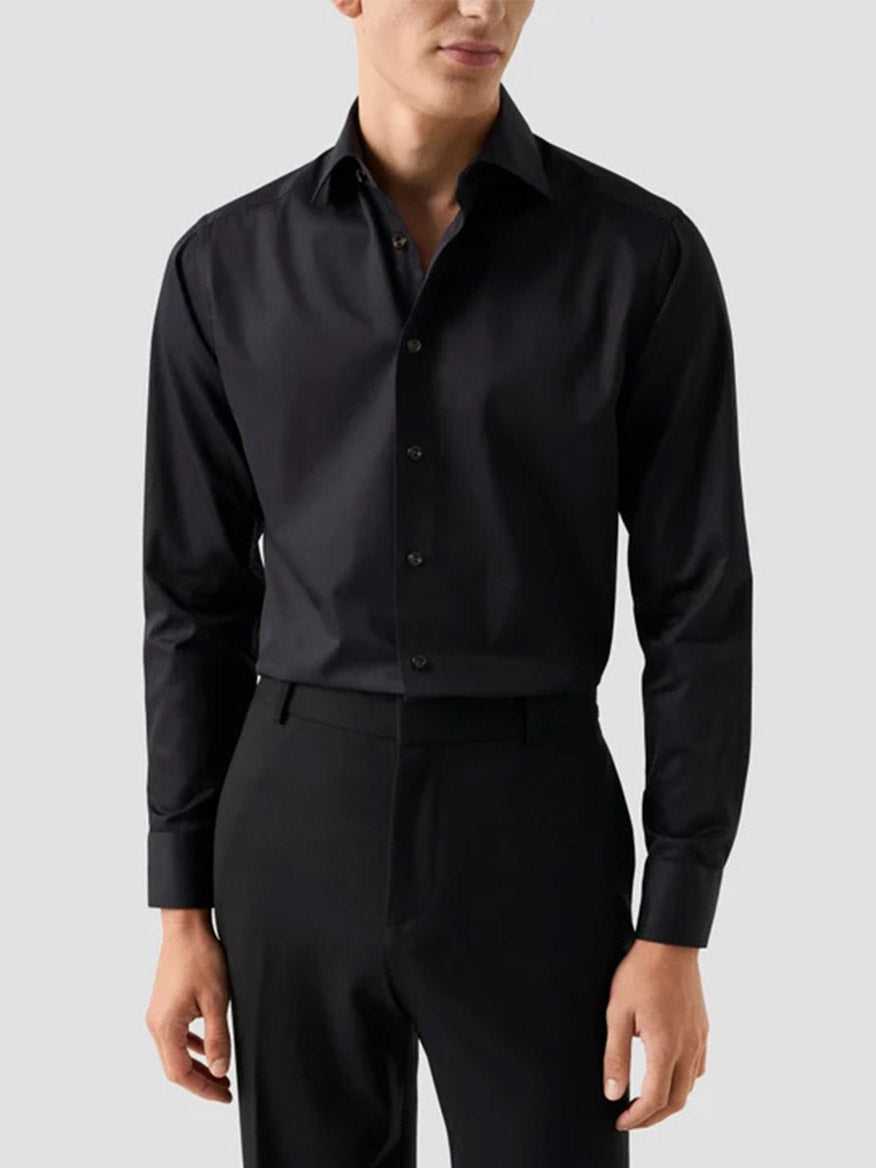 A man wearing an Eton Slim Fit Solid Elevated Twill Dress Shirt in black with matching trousers.