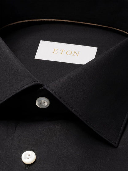 Close-up of the Eton Slim Fit Solid Elevated Twill Dress Shirt in black, featuring white buttons and an Eton label inside the collar, showcasing its refined style.