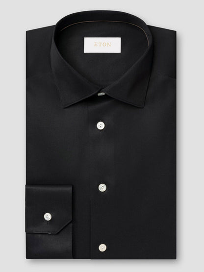 A neatly folded Eton Slim Fit Solid Elevated Twill Dress Shirt in black, with white buttons and a visible Eton label inside the collar.