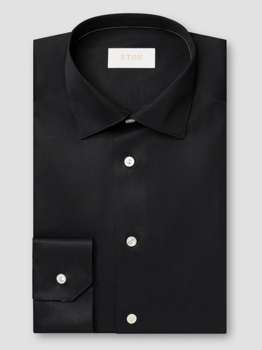 A neatly folded Eton Slim Fit Solid Elevated Twill Dress Shirt in black, with white buttons and a visible Eton label inside the collar.